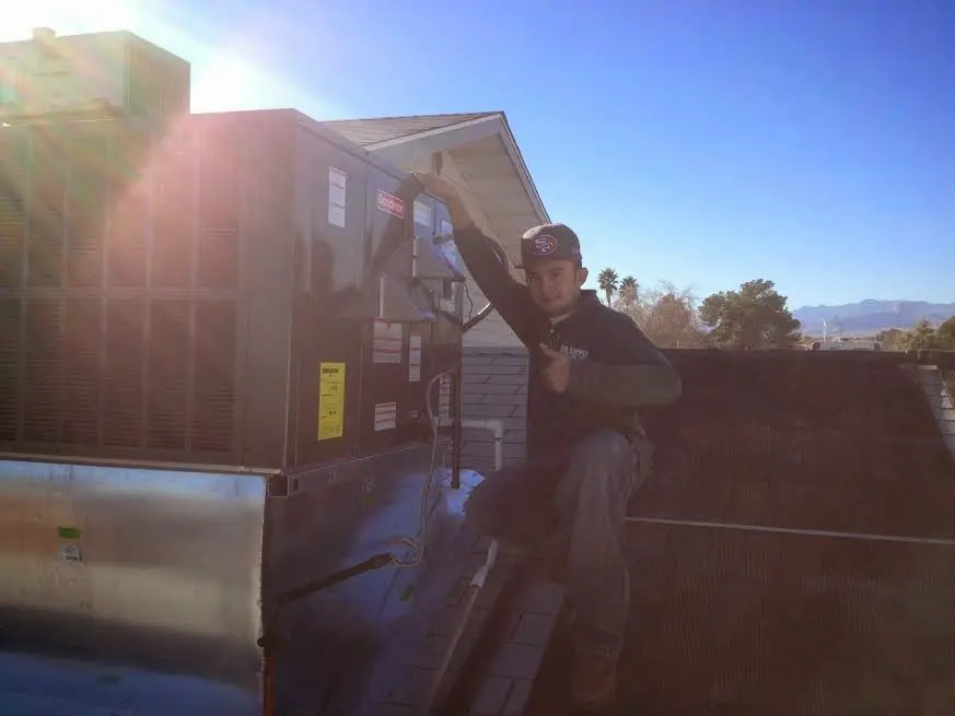 HVAC technician performing Heat Pump Repair on a rooftop unit in Norwood